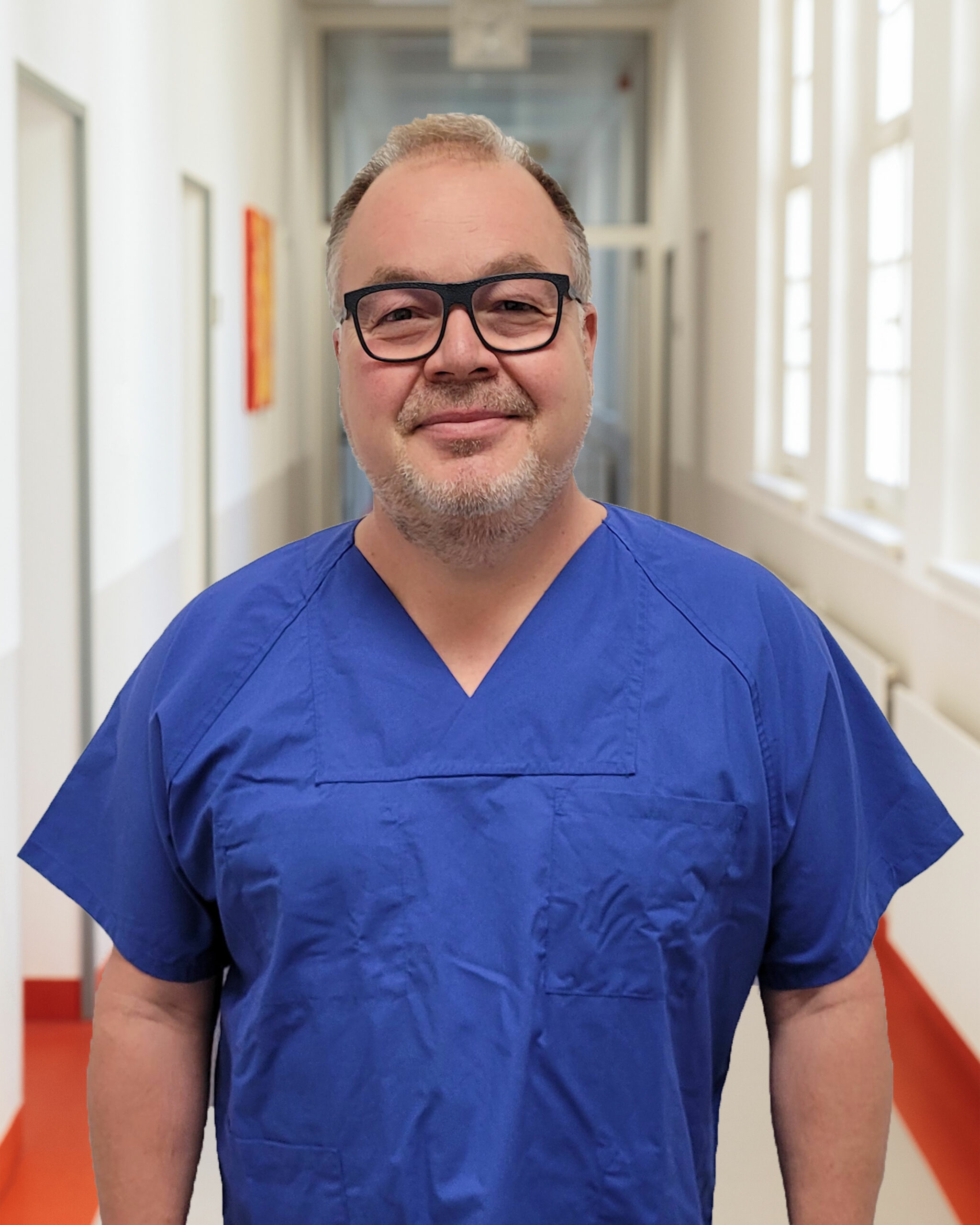Portrait von Dr. med Peter Jungberg vor Klinikkorridor